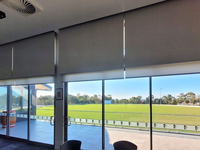 Commercial roller blinds above glass doors in a Cranbourne function room overlooking an oval
