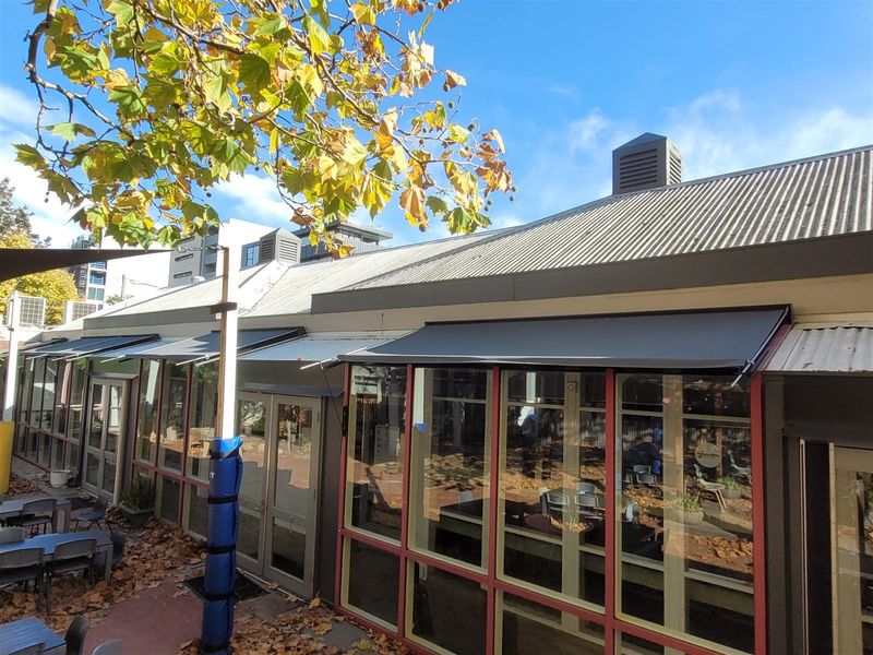 Folding arm awnings over a commercial outdoor seating area
