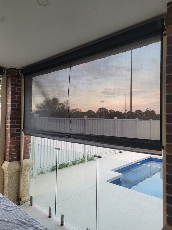 Outdoor blinds enclosing an alfresco area beside a pool fence