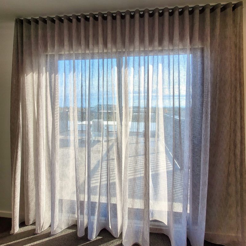 Double S-fold curtains, sheer and blockout, on a bedroom window in Brighton