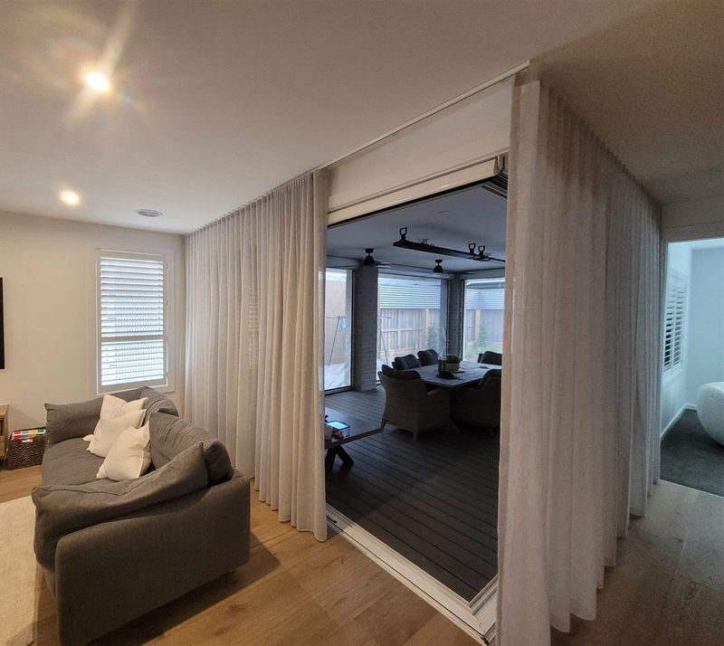 Living room with plantation shutters on the windows and sheer curtains on the glass doors