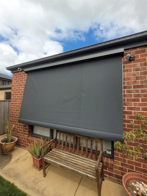 Straight drop awning lowered over a window on a brick home