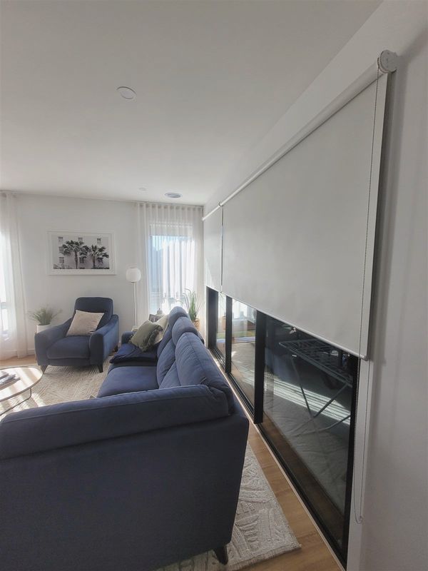 Sunscreen roller blind lowered over a living room glass door