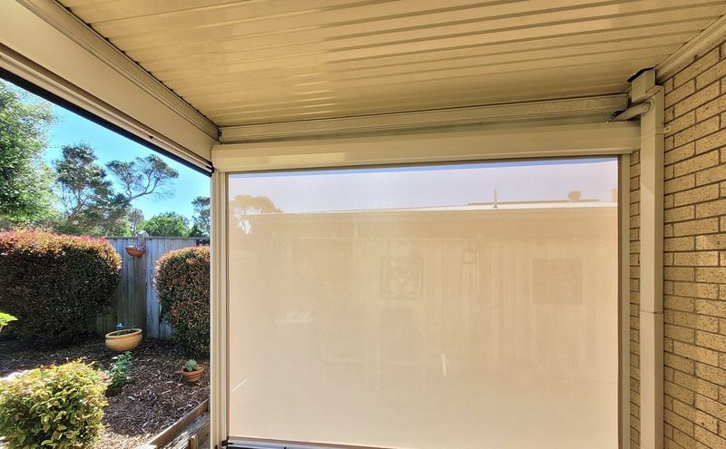Cream zip track blind lowered across a paved patio in Cowes